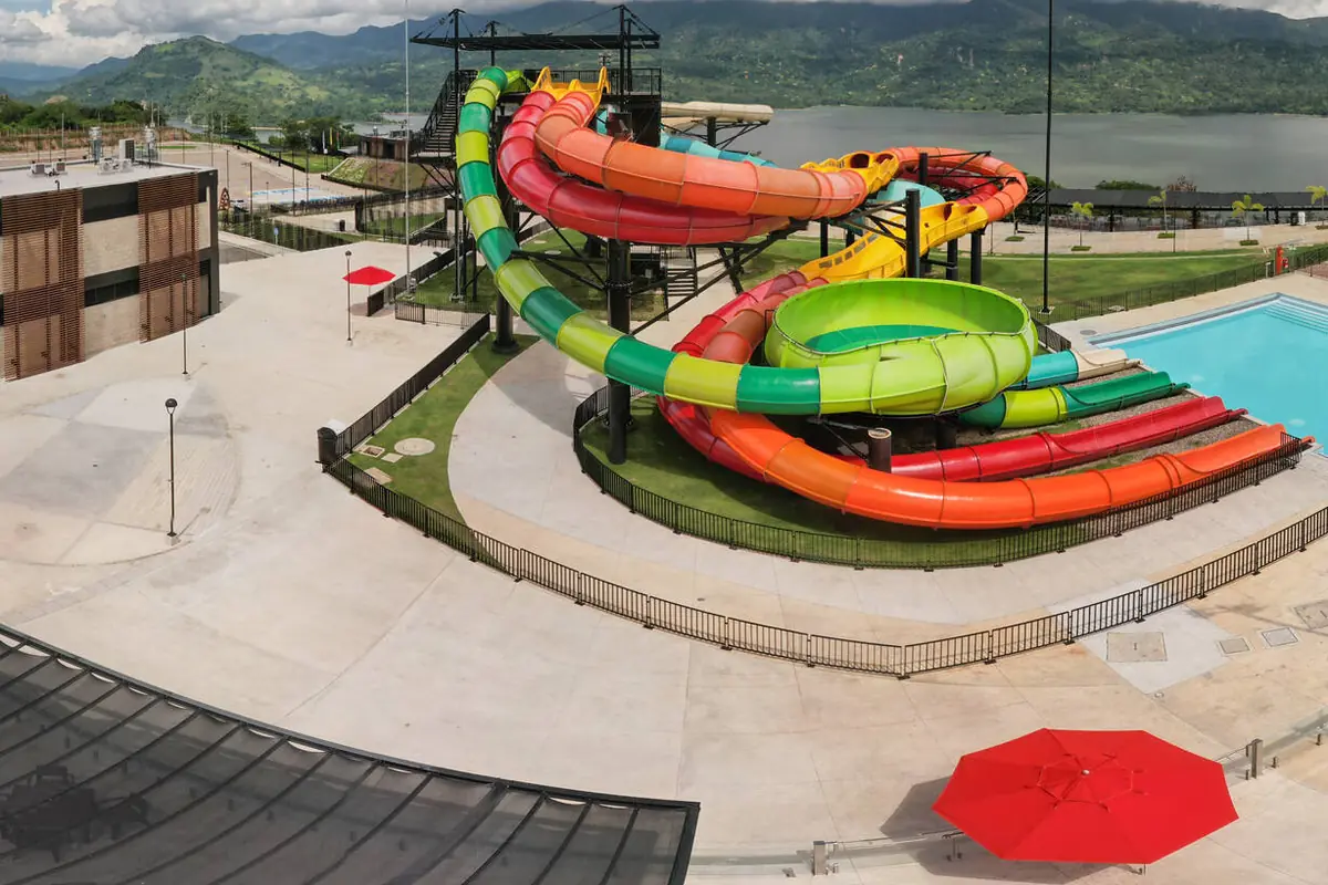 Toboganes de colores del Twister con la piscina de llegada y el embalse al fondo
